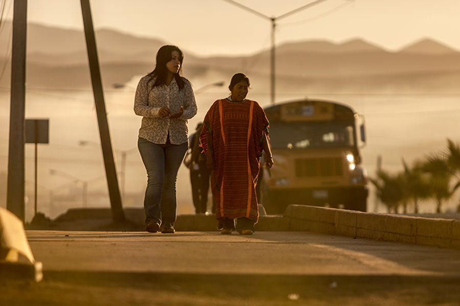 Amelia walks along the street with a Triqui woman.